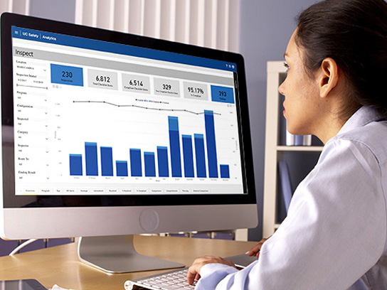 ffice worker utilizing RSS's Inspect Solution on a desktop computer, with graphs and analytics visible on the screen.