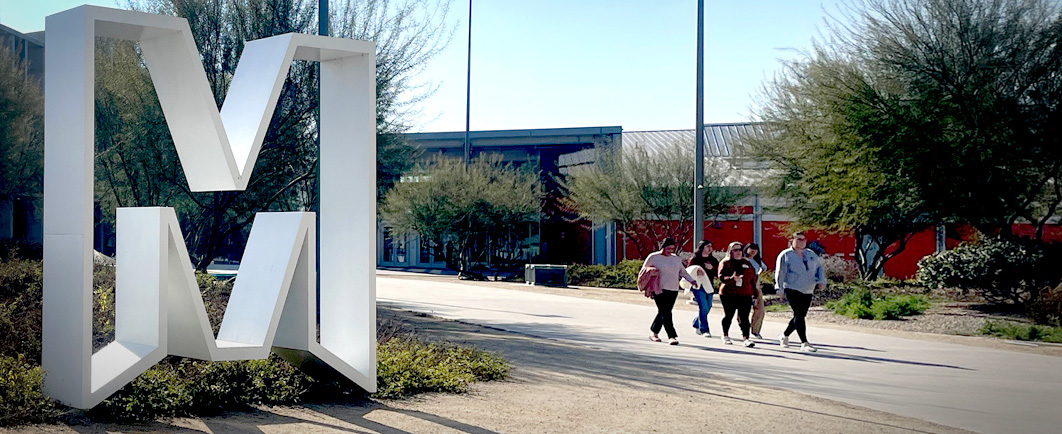 UC Merced "M" statue with unidentifiable students walking in the background on campus