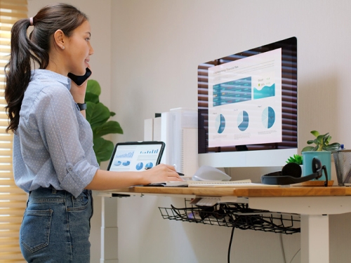 Person working on a computer, standing with an elevated desk